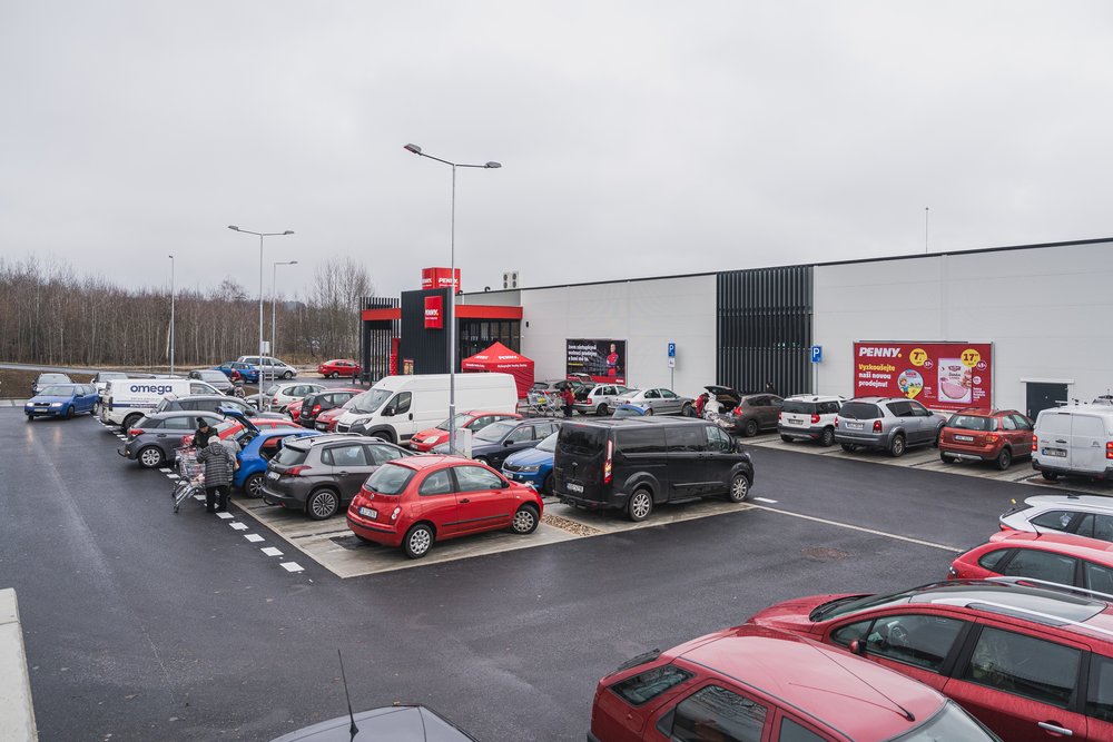 Zaplněné parkoviště před první etapou retail parku Lužická, vpravo vstup do Penny